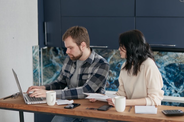 Couple reviewing health insurance paperwork and bills at kitchen table
